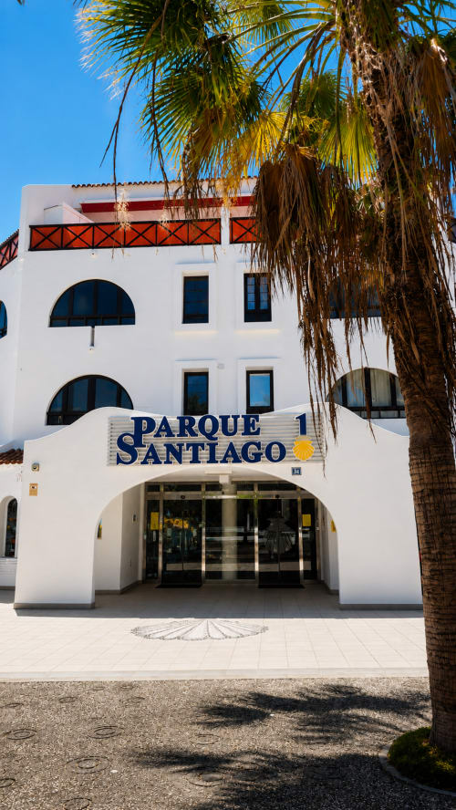 Parque Santiago I building entrance in Playa de Las Americas, Tenerife with white facade and palm trees