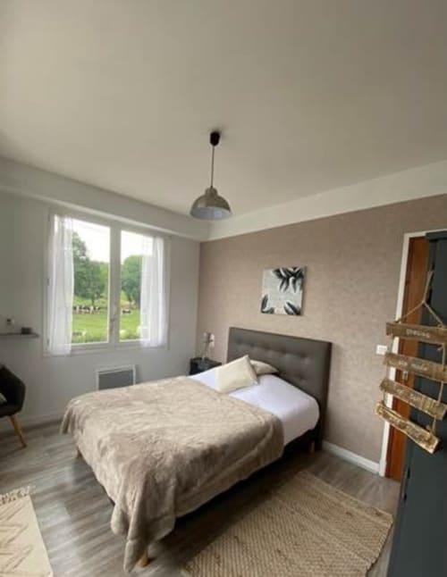 Chambre douillette à La Maison de Barlest avec lit simple, murs beige et vue sur le jardin par de grandes fenêtres