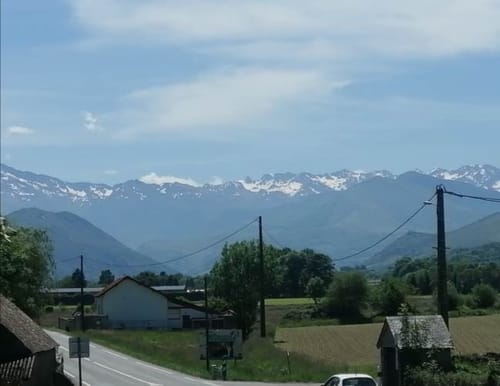 Vue de la vallée alpine depuis La Maison de Barlest avec montagnes enneigées, fermes et prés verdoyants