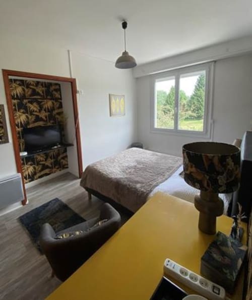 Chambre tropicale à La Maison de Barlest B&B avec lit, fauteuil, bureau jaune et vue sur le jardin