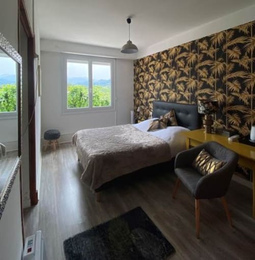 Chambre tropicale à La Maison de Barlest avec papier peint palmettes, vue montagne et mobilier contemporain