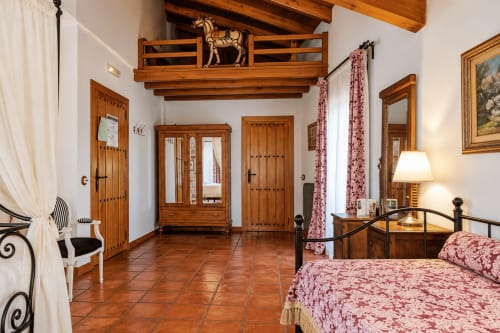Habitación espaciosa en El descanso del peregrino B&B en Guadalupe con vigas de madera rústica, pisos de terracota y decoración tradicional