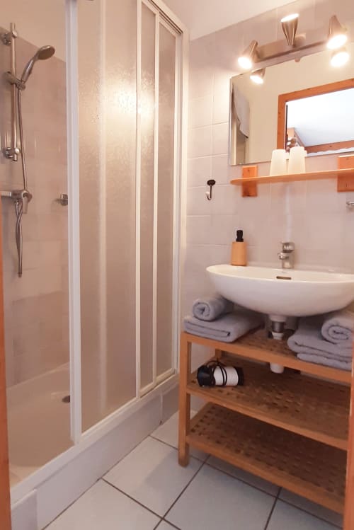 Salle de bain moderne avec douche à l'italienne, lavabo blanc, étagères en bois et miroir au Chalet De La Yodine, Feissons sur Salins
