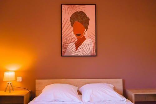 Modern bedroom in Nairobi Apartment at Résidence des Sables with contemporary portrait art above bed and warm orange ambient