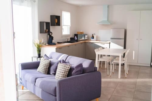 Modern open-plan apartment at Résidence des Sables with purple sofa, white dining table, and equipped kitchen in Mably,