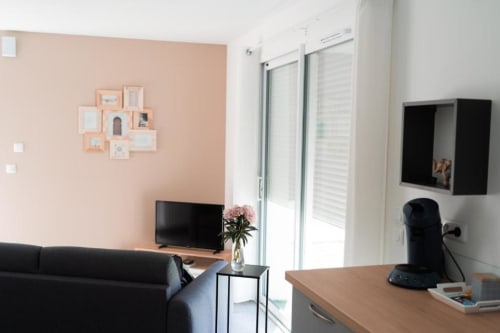 Modern living room in New Delhi Apartment at Résidence des Sables with peach accent wall, sofa, and flat-screen TV