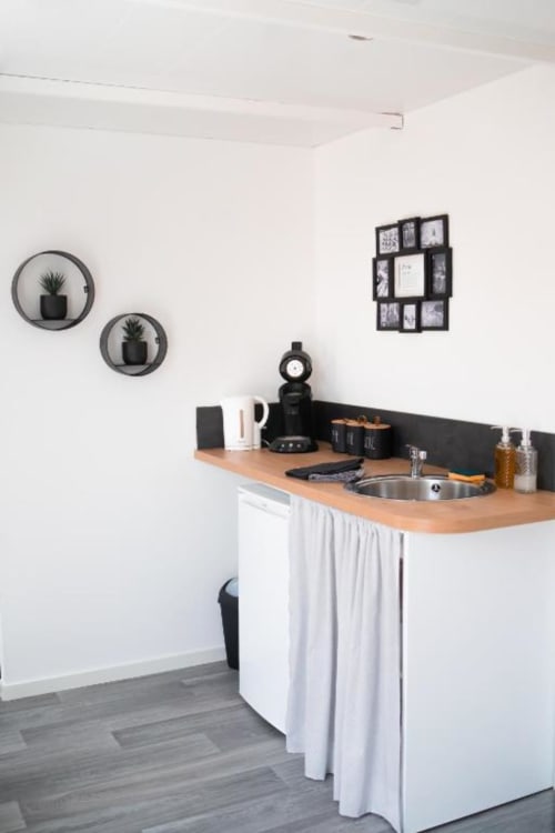 Modern kitchenette in New York Apartment at Résidence des Sables with wooden countertop, sink, and wall-mounted plant holders
