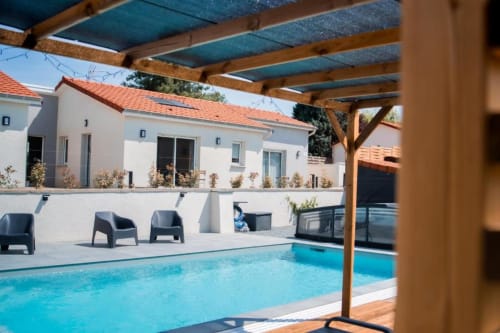 Résidence des Sables pool area with turquoise water, wooden pergola, loungers, and white apartments with red-tiled roofs in