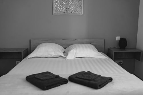 Modern bedroom in New Delhi Apartment at Résidence des Sables with two white pillows and folded towels on striped bed