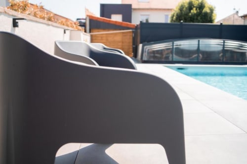Modern poolside lounge chairs at Résidence des Sables, Mably with terrace view and retractable pool enclosure