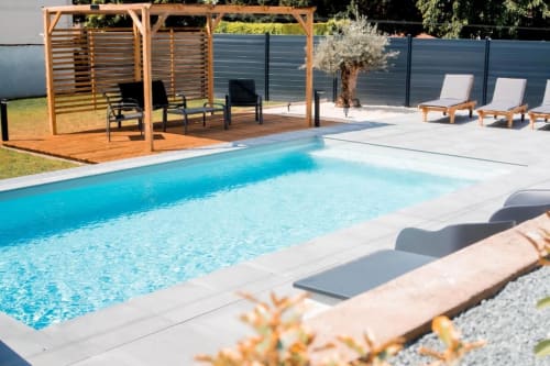 Modern pool with loungers, wooden pergola, and terrace at Résidence des Sables in Mably, France
