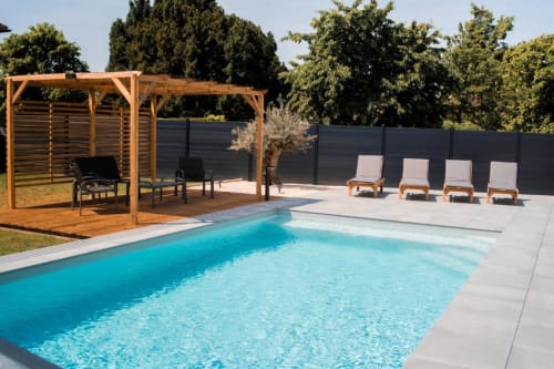 Luxury swimming pool with turquoise water, wooden pergola lounge area, and sunbeds at Résidence des Sables in Mably