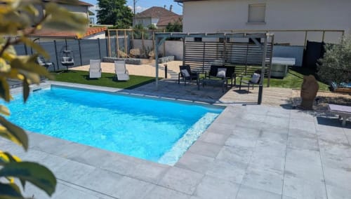 Bright blue swimming pool with terrace seating at Résidence des Sables in Mably, France