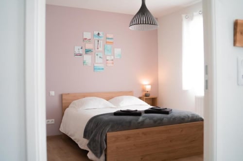 Modern bedroom in Sydney Apartment at Résidence des Sables, Mably with pink walls, wooden bed, and coastal décor