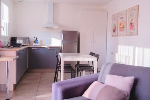 Modern Paris apartment at Résidence des Sables with pink walls, equipped kitchen, dining area, and purple sofa in Mably,