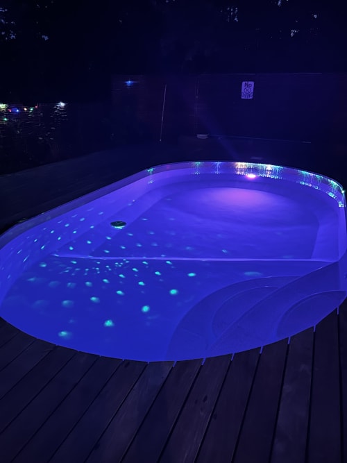 Piscine ovale illuminée la nuit avec éclairage LED bleu à la villa Dream Properties à La Teste-de-Buch