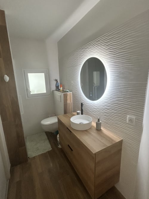 Salle de bain moderne de la villa Dream Properties près de la plage de La Teste-de-Buch, avec miroir ovale illuminé et lavabo en céramique blanche