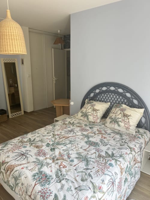 Chambre moderne avec parure tropicale, tête de lit en rotin gris et luminaire suspendu tressé dans villa à La Teste-de-Buch