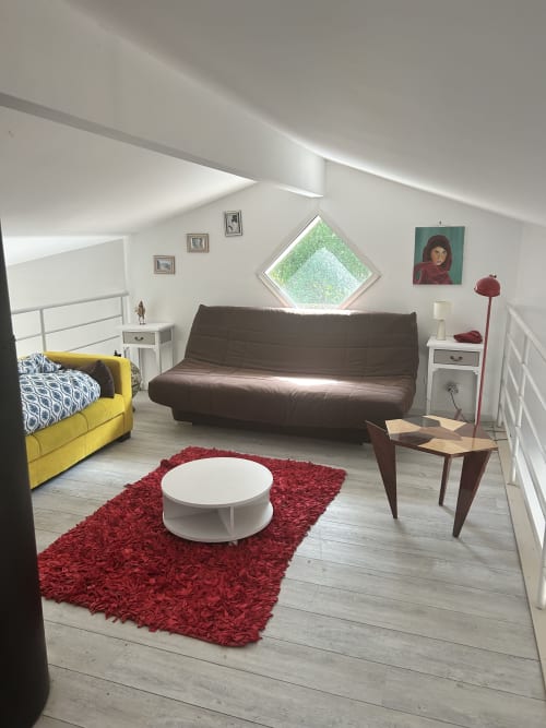 Villa moderne avec salon accueillant : fauteuil jaune, canapé marron, tapis rouge, table basse blanche et vue sur le jardin près de La Teste-de-Buch
