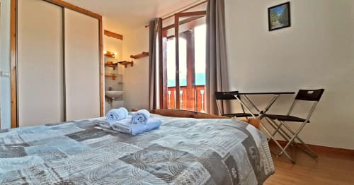 Chambre lumineuse au Chalet De La Yodine avec lit double, salle de bain partagée, balcon vue montagne et mobilier en bois.