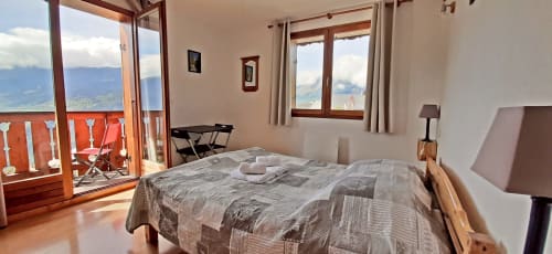 Chambre lumineuse avec vue panoramique sur les montagnes au Chalet De La Yodine, balcon, lit double et paysages alpins