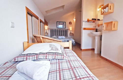 Chambre familiale cosy du Chalet De La Yodine avec literie écossaise, mobilier en bois, salle de bain attenante et balcon montagne