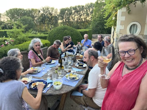 Des clients savourant un dîner en plein air à la Cour Du Liège, un gîte à Baugé-en-Anjou, dans un jardin paysagé.