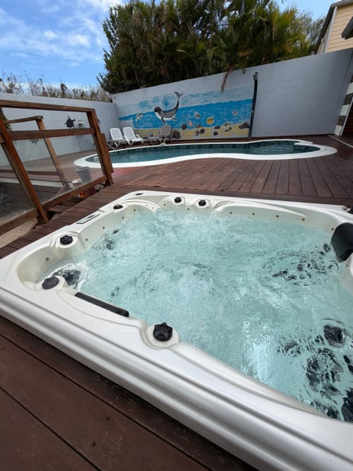 Spa bouillonnant sur terrasse bois à la villa Le Domaine Des Doudous à Saint-Pierre, Réunion, avec piscine et fresque océanique