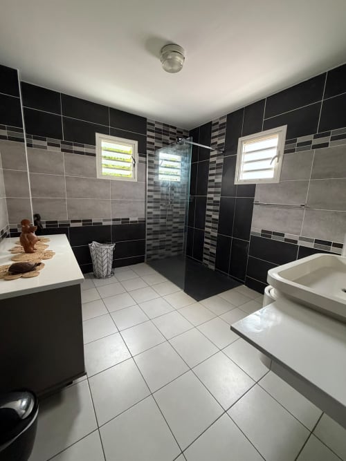 Salle de bain moderne de la villa Le Domaine Des Doudous avec carrelage noir et gris, douche à l'italienne, meuble vasque et baignoire