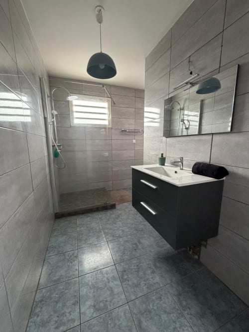 Salle de bain moderne de la villa La Case à Nath au Domaine Des Doudous, Saint-Pierre avec vasque noire, carrelage gris et verre