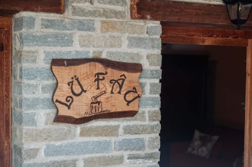 Cartello in legno con testo italiano su muro in pietra a Borgo Maira, rifugio montano di Prazzo