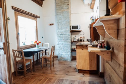 Accogliente cucina e zona pranzo al Borgo Maira Village a Prazzo con mobili in legno, camino in mattoni e vista montagna