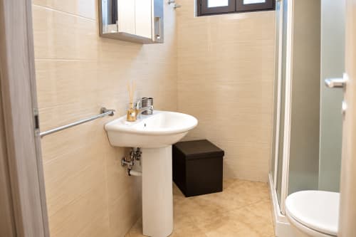 Modern bathroom with pedestal sink, mirror, and shower in Catania apartment