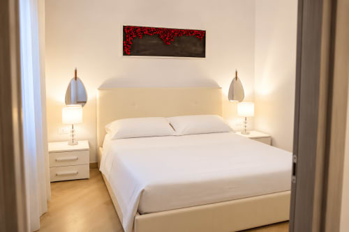 Modern bedroom in Sicily In Home apartment, Catania with queen bed, white bedding, pendant lamps, nightstands, and artwork.