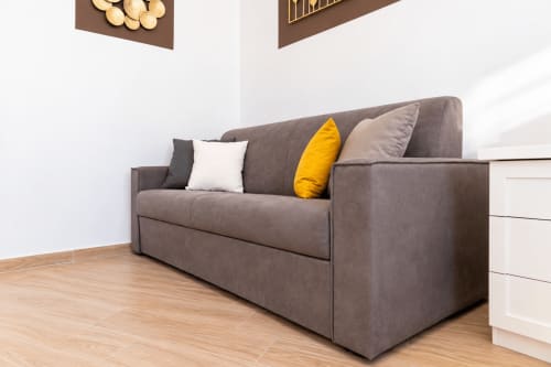 Gray upholstered sofa with yellow and beige pillows in modern apartment at Sicily In Home, Catania