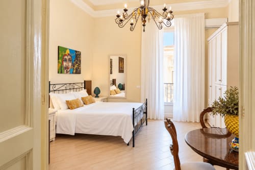 Bright bedroom with wrought iron bed, golden accents, and Catania city view at Sicily In Home apartment