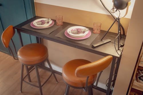 Elegant dining setup at Sicily In Home Catania with two place settings, pink plates, and cognac leather bar stools