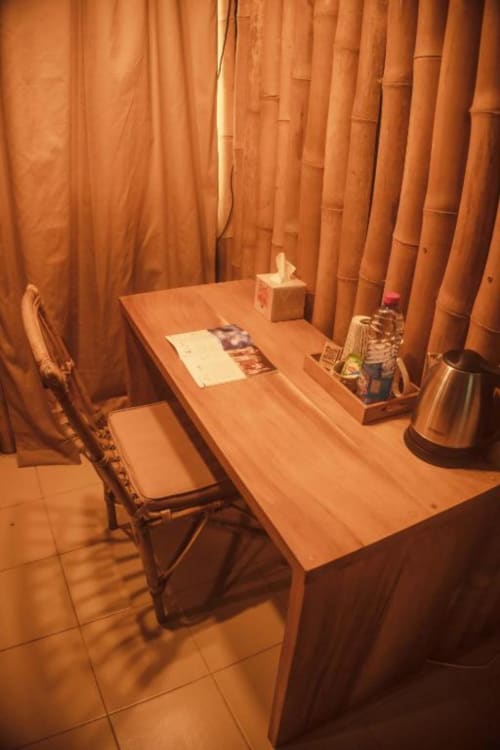 Cozy private workspace at NOMADS EN BORD DE MER, Lomé with wooden table, chair, and orange curtains