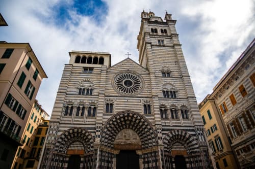 La facciata ornamentale a strisce della Cattedrale di Genova con campanile e ingresso ad archi, vicino a La Superba Stay Genova