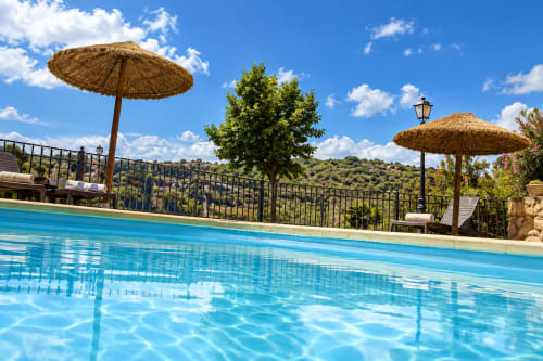 Lujosa piscina con sombrillas de palma con vistas a la campiña de Guadalupe en El descanso del peregrino