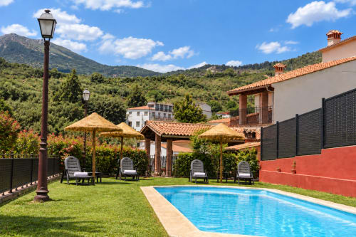 Zona de piscina El descanso del peregrino en Guadalupe, Cáceres con tumbonas, pérgolas y vistas a las montañas