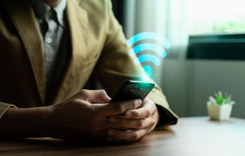 Homme d'affaires tenant un smartphone avec signal WiFi à La Maison de Barlest, Barlest