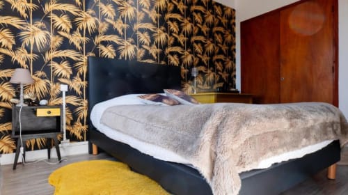 Chambre élégante à La Maison de Barlest avec lit noir, papier peint palmettes dorées et tapis jaune