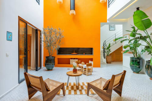Lounge contemporain du patio à M Résidences et Hôtels à Grasse avec murs orange vif, chaises en bois et plantes en pots