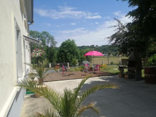 Terrasse du jardin de la Maison de Barlest avec parasol rose et salon donnant sur la campagne française