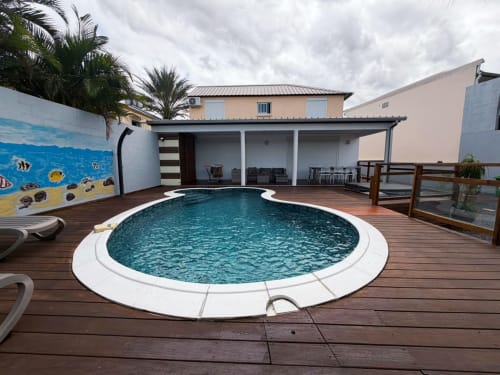 Piscine circulaire sur terrasse en bois au Domaine Des Doudous B&B à Saint-Pierre, Réunion, avec palmiers tropicaux et patio couvert
