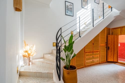 Escalier contemporain aux M Résidences Grasse avec rampe noire, murs blancs, portes en bois et plante en pot