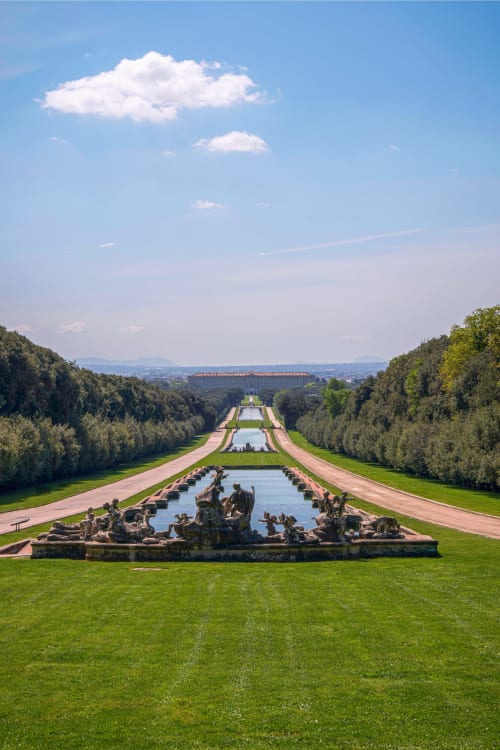 Giardini sontuosi con fontane scultoree, canale alberato e ponte acquedotto in lontananza presso Vietri, Italia
