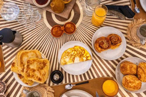 Petit-déjeuner à M Résidences et Hôtels à Grasse : viennoiseries, crêpes, croissants, jus frais et café sur nappe rayée
