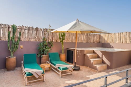 Terrasse ensoleillée aux M Résidences Grasse avec chaises longues, parasol, cactus et bain à remous